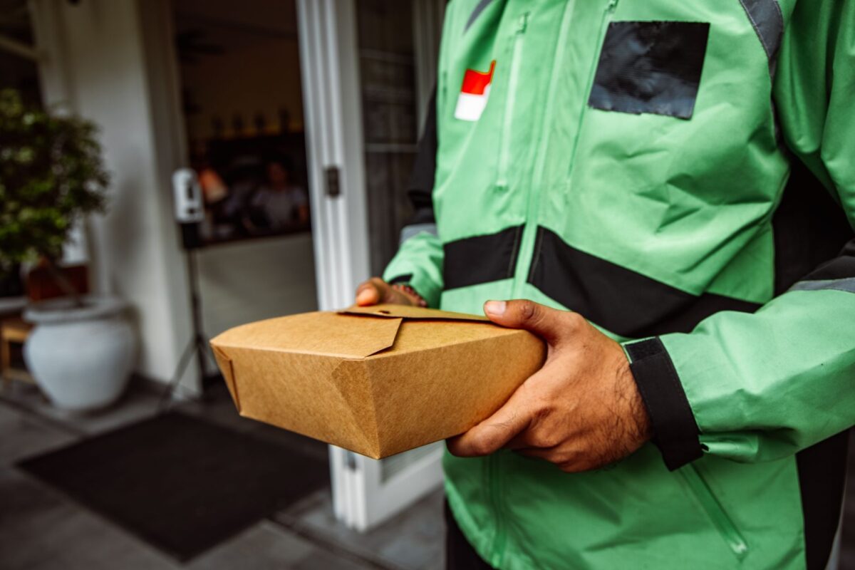 Livreur en veste verte tenant un sac de livraison de repas