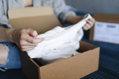 Personne déballant un vêtement d'un colis en carton sur une table